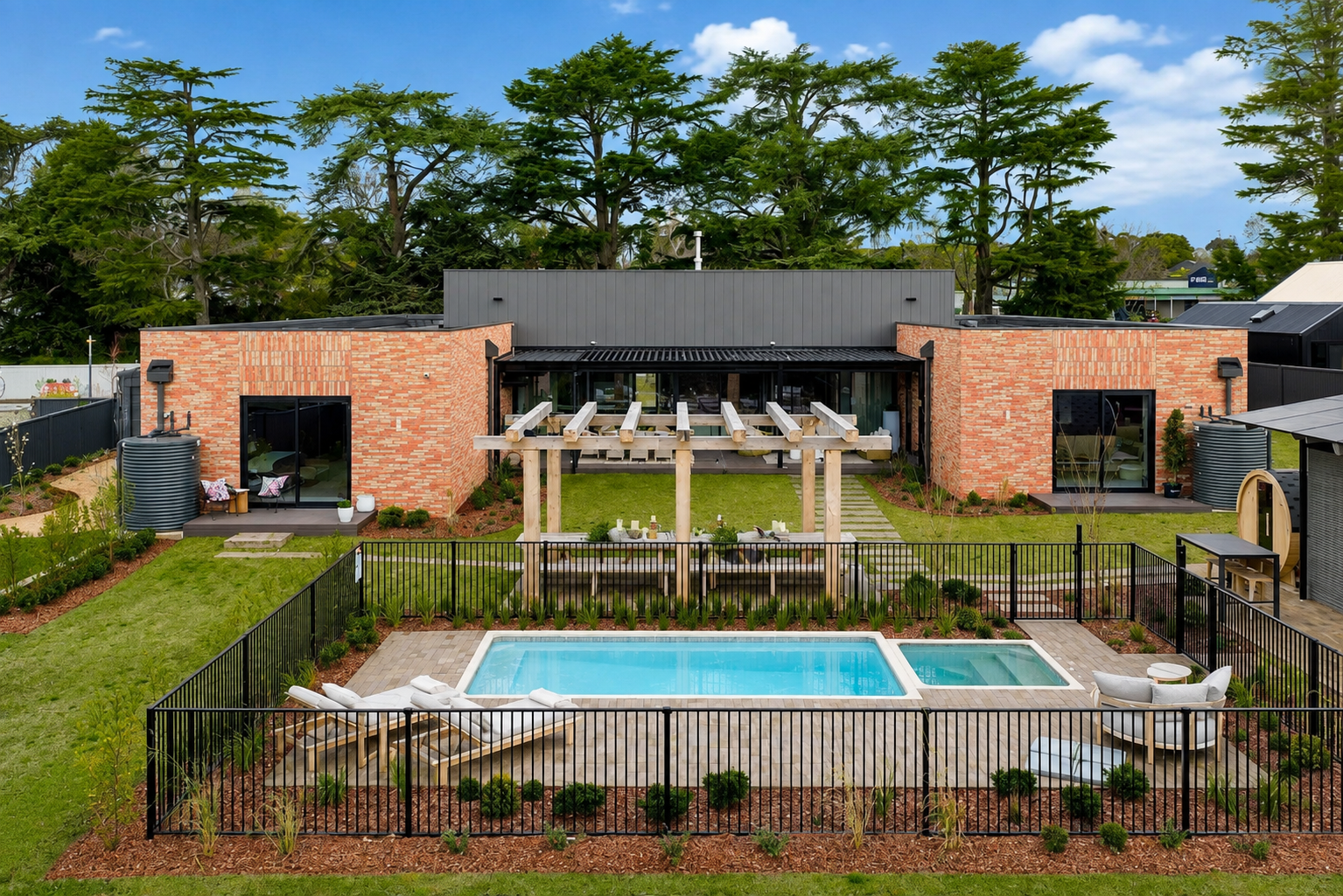 Completed Melbourne residential landscape with paved pool surround, pergola, lawn and garden beds